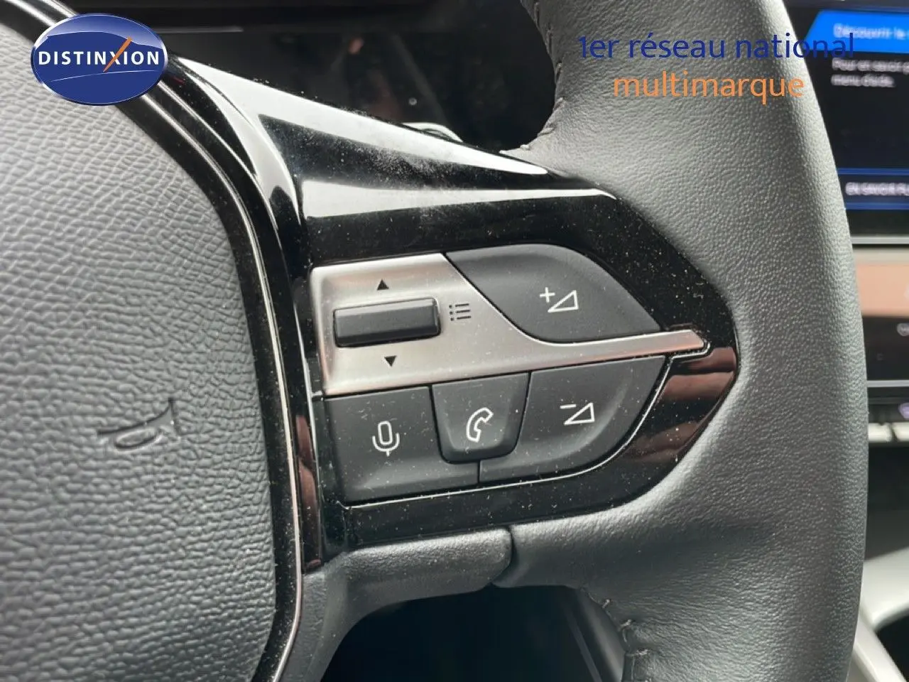 Gros plan sur les commandes multifonctions à gauche du volant en cuir noir du Peugeot 408 gris Selenium 2025.