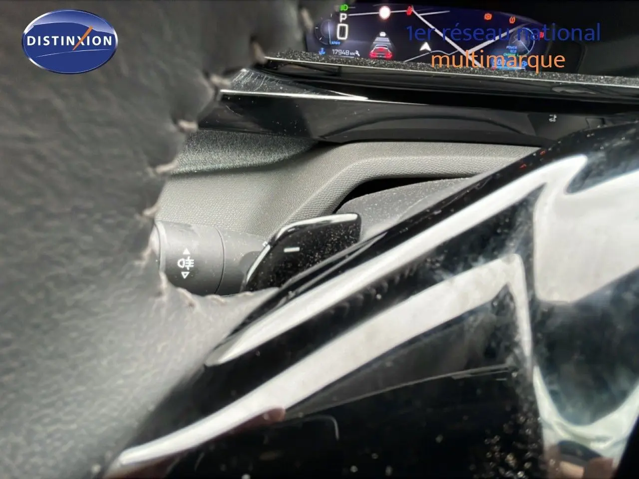 Gros plan sur le volant et le combiné d'instruments numérique de la Peugeot 408 1.2 Hybrid 2025, intérieur gris noir.