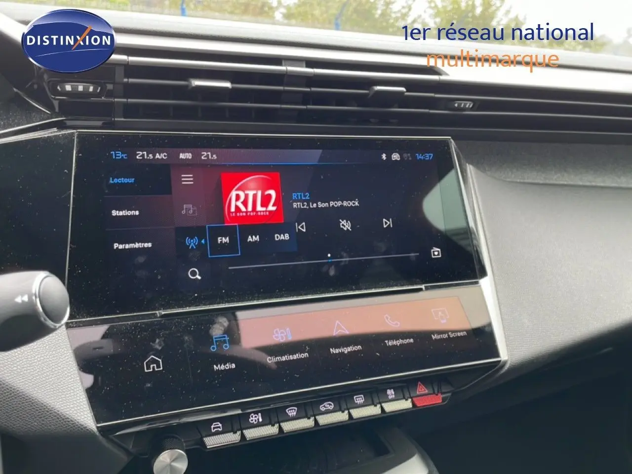 Vue rapprochée de l’écran tactile central du tableau de bord du Peugeot 408 gris, affichant la radio RTL2.