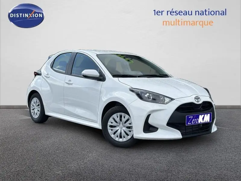 Toyota Yaris 116h Dynamic blanc lunaire vue 3/4 avant droit avec calandre noire et jantes acier.