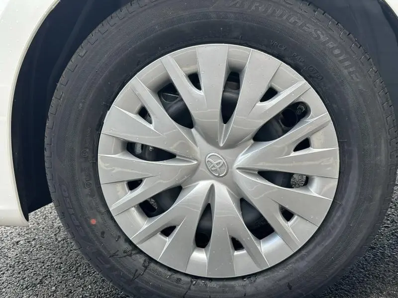 Gros plan sur la roue avant gauche de la Toyota Yaris 116h Dynamic 2025 en Blanc Lunaire avec enjoliveur argenté et logo Toyota.