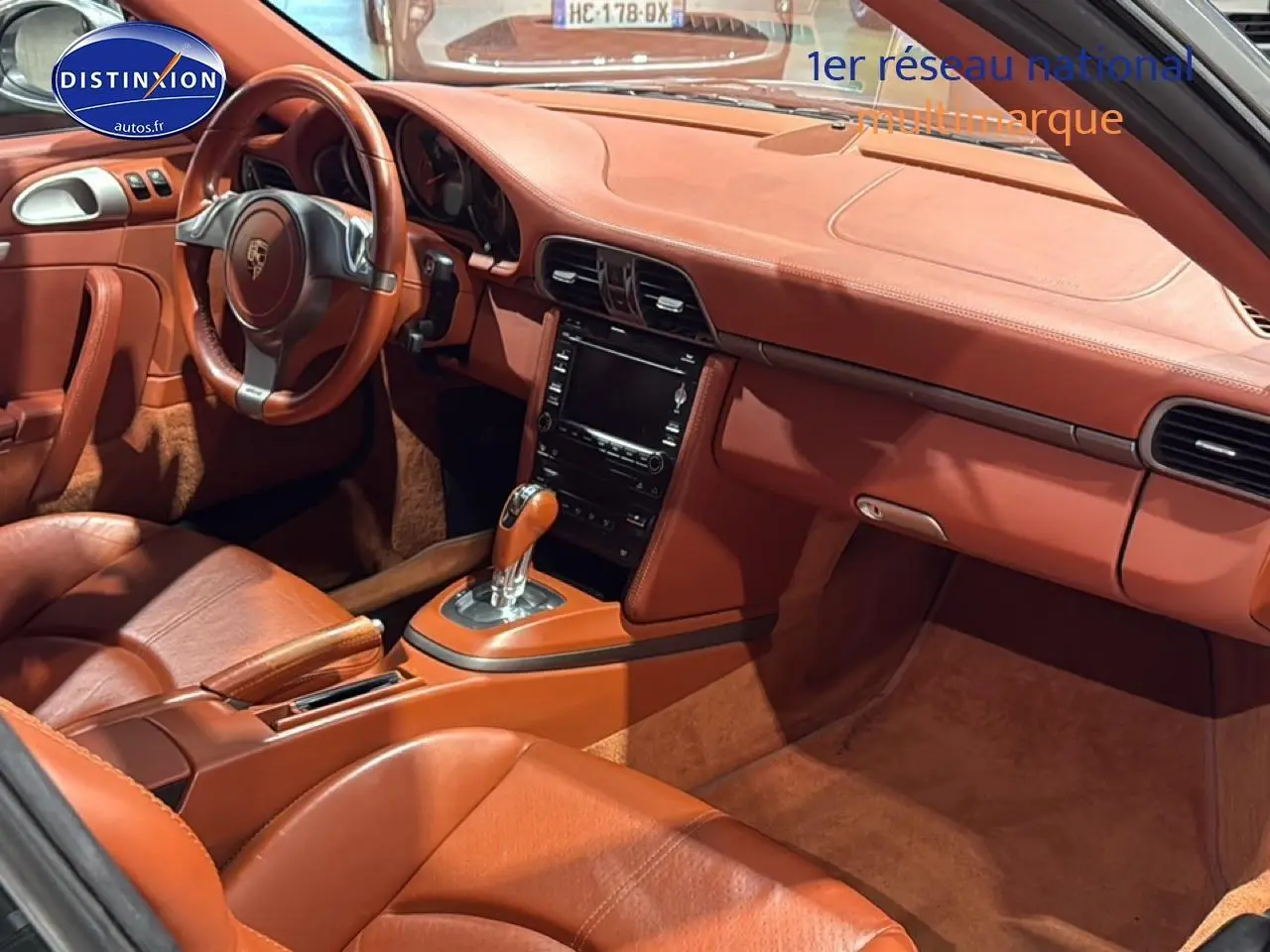 Vue intérieure côté conducteur de la Porsche 911 (997) carrera pdk 2009 avec cuir brun et console centrale automatique.