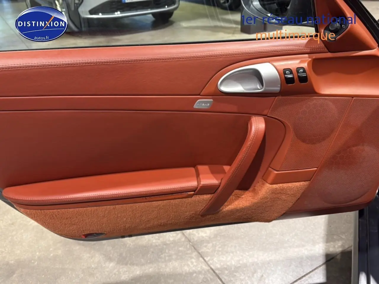 Détail de la porte côté conducteur en cuir marron rouge de la Porsche 911 (997) Carrera PDK gris, avec commande vitres et poignée alu.