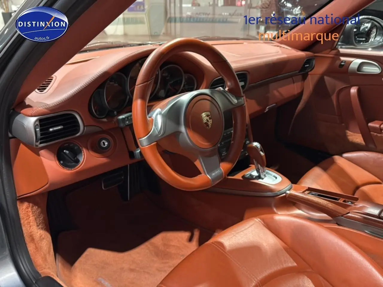 Vue intérieure côté conducteur de la Porsche 911 (997) carrera pdk 2009 avec cuir marron et volant sport.