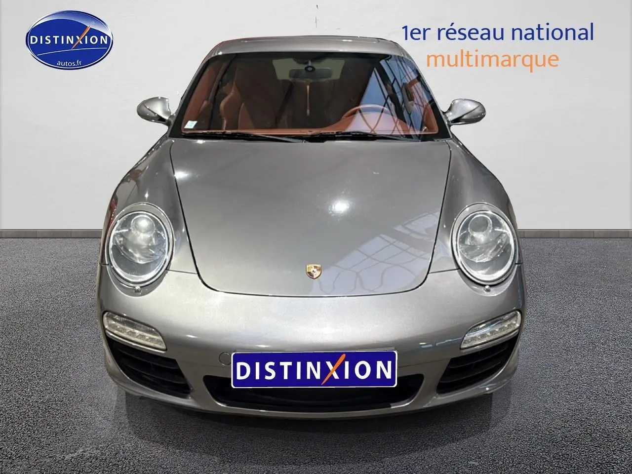 Vue frontale d'une Porsche 911 (997) carrera pdk gris métallisé avec phares bi-xénon et intérieur cuir marron visible.