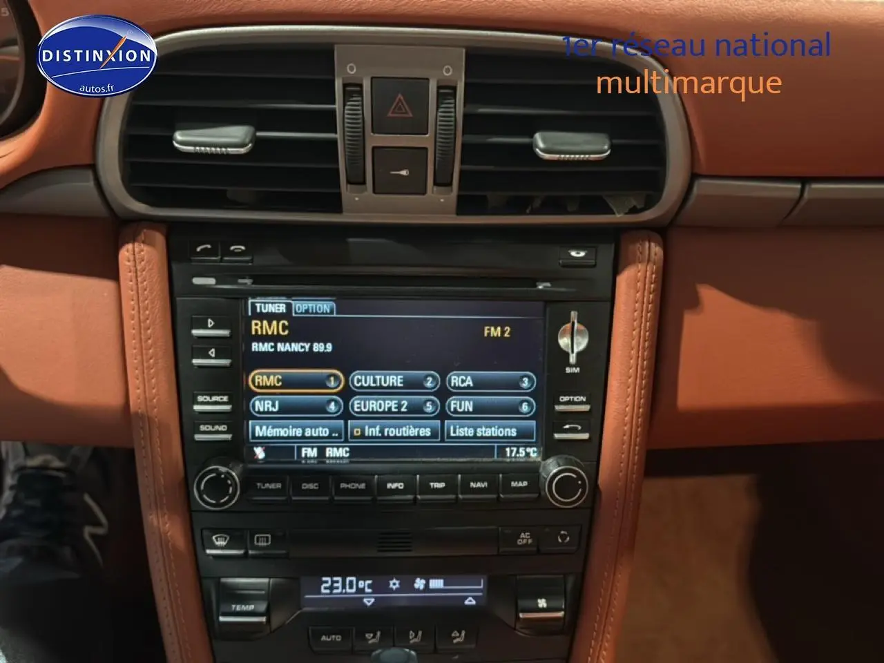 Vue rapprochée de la console centrale en cuir marron du Porsche 911 (997) carrera pdk avec écran multimédia et commandes clim.