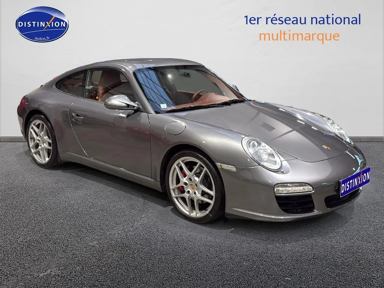 Porsche 911 (997) carrera pdk gris vue 3/4 avant droit, jantes alu et phares bi-xénon visibles.