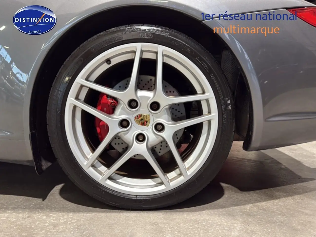 Gros plan sur la jante alu argentée et le frein rouge d'une Porsche 911 (997) carrera gris côté arrière droit.