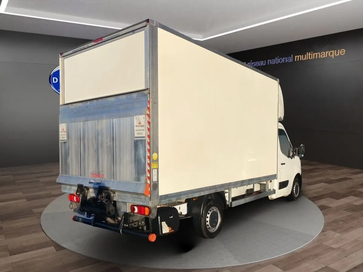 Vue 3/4 arrière droite d’un utilitaire Renault Master blanc avec caisse fermée et hayon élévateur métallique.