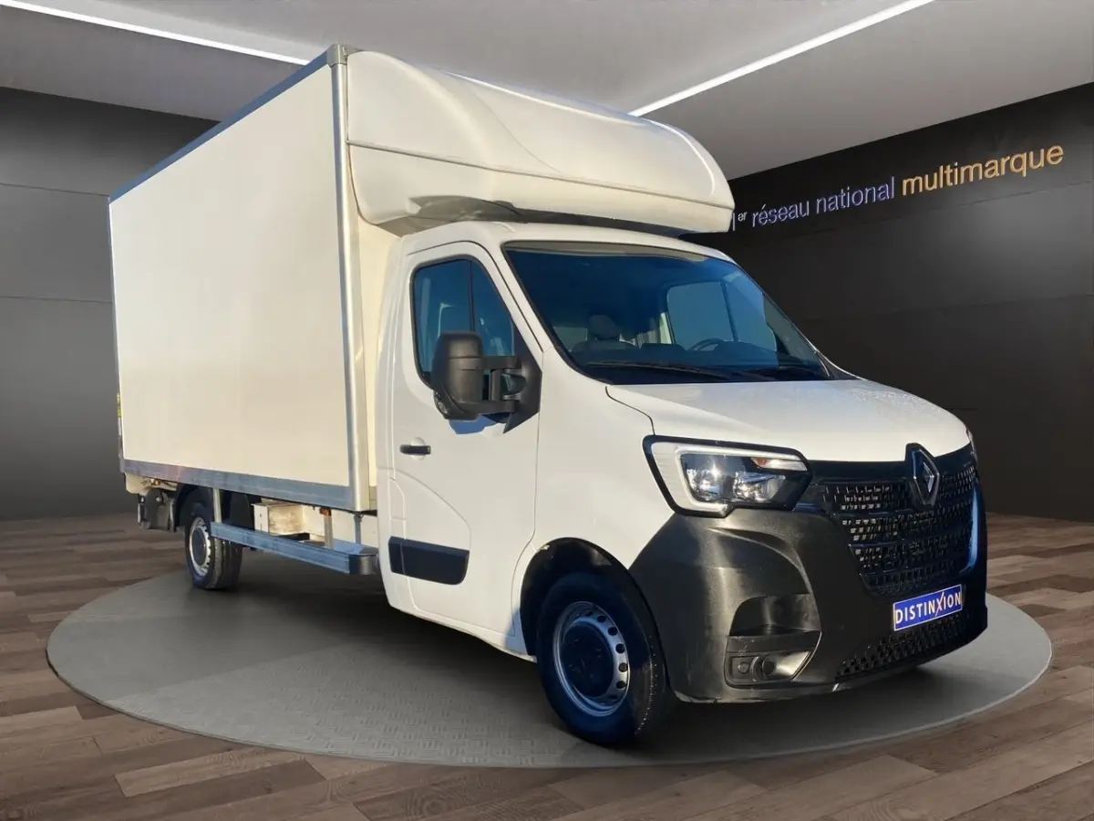 Renault Master blanc en 3/4 avant droit, châssis cabine avec grande caisse et hayon élévateur visible.