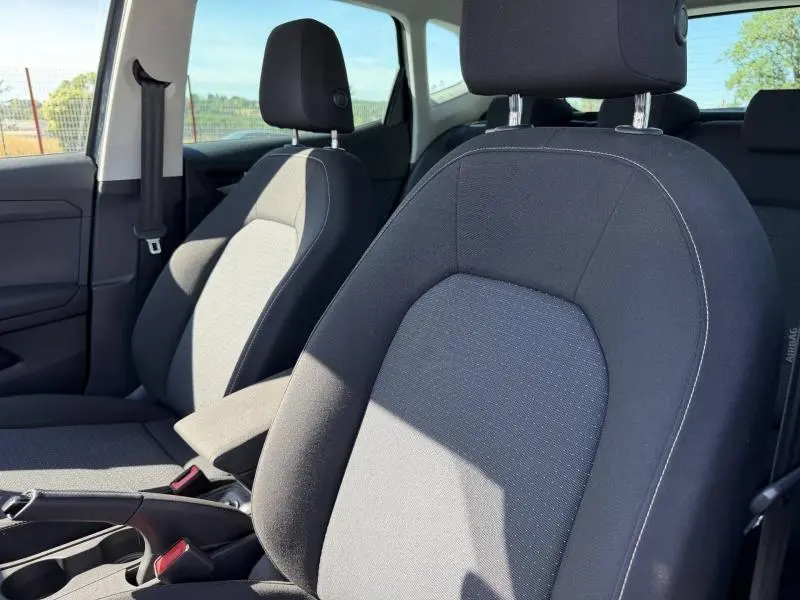 Vue intérieure rapprochée des sièges avant en tissu gris du SEAT Arona 2025, avec accoudoir central visible.