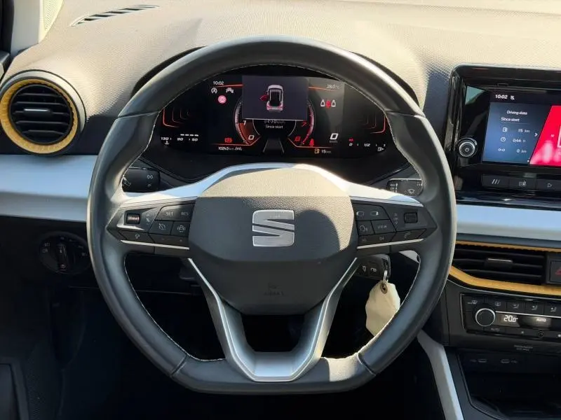Vue intérieure centrée sur le volant cuir multifonction d'une SEAT Arona gris Magnétique Métal avec tableau de bord numérique.