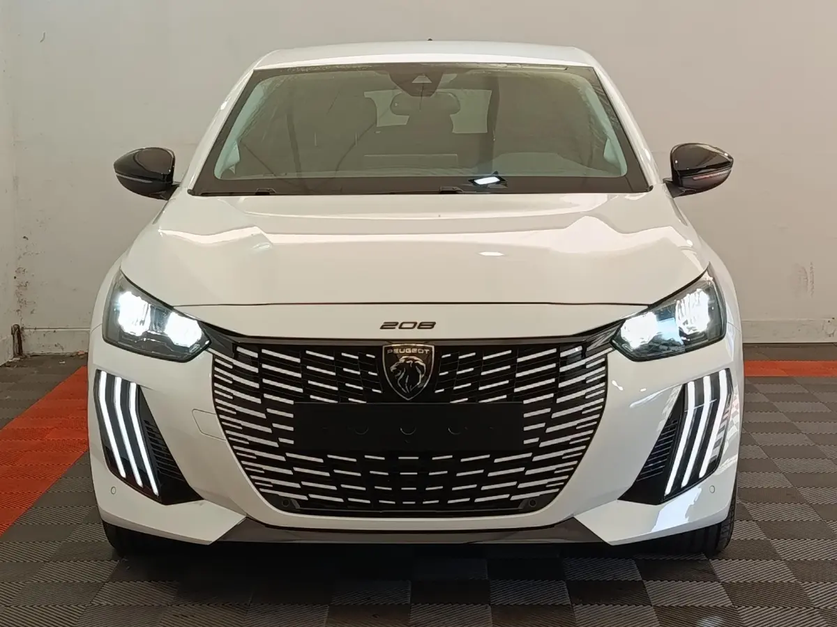 Vue frontale d'une Peugeot 208 électrique blanche 2024 avec phares LED et calandre noire distinctive.
