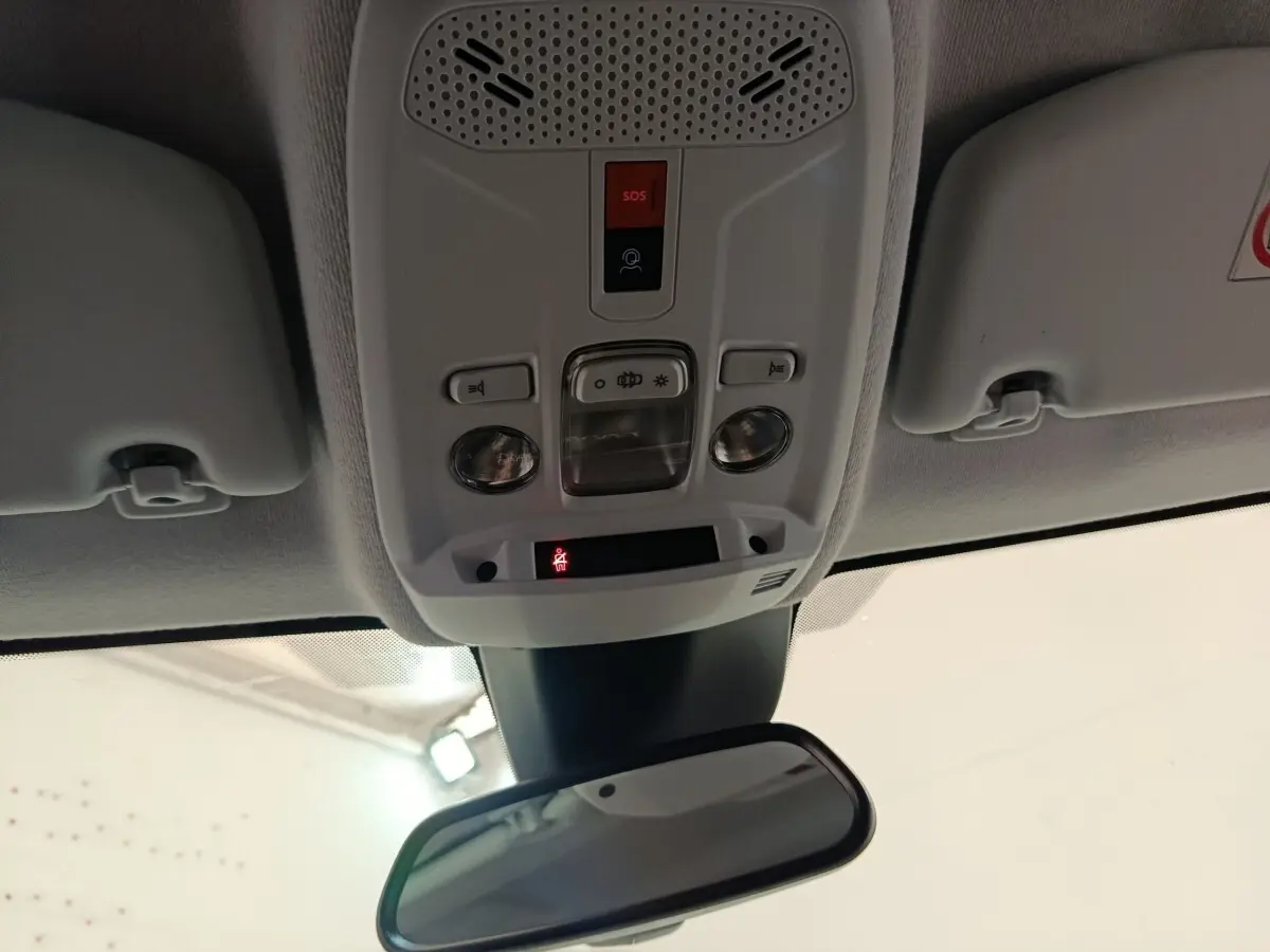 Plafonnier intérieur avec commandes d’éclairage et bouton SOS, vue centrée vers le rétroviseur intérieur d’une Peugeot 208 blanche.