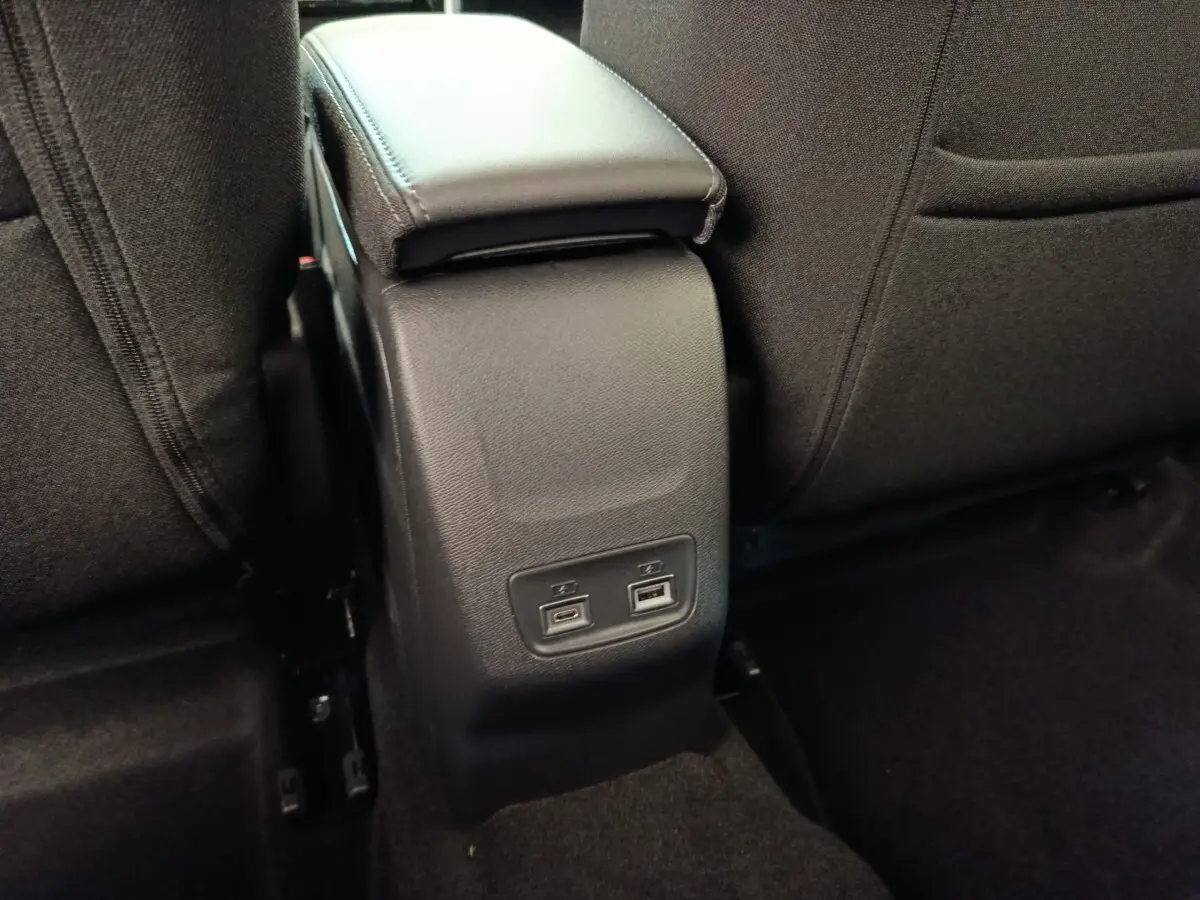 Vue rapprochée de la console centrale arrière noire avec ports USB dans l’habitacle du Peugeot 208 électrique blanc.