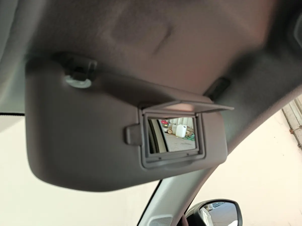 Détail intérieur du pare-soleil avec miroir ouvert côté conducteur d'une Peugeot 208 électrique blanche 2024.