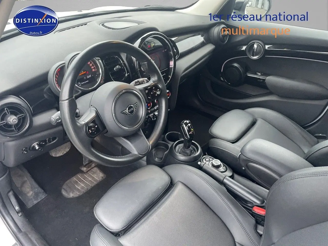 Vue intérieure côté conducteur d'une MINI 1.5 136CH 2023 avec sellerie cuir noir et console centrale moderne.