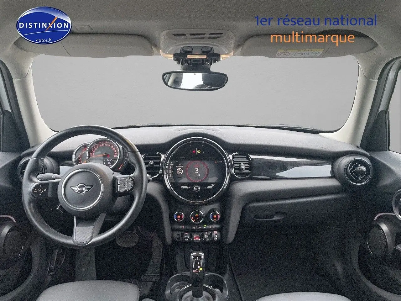 Tableau de bord et volant de MINI 1.5 136CH blanc nacré, vue frontale intérieure mettant en valeur l'écran central rond.