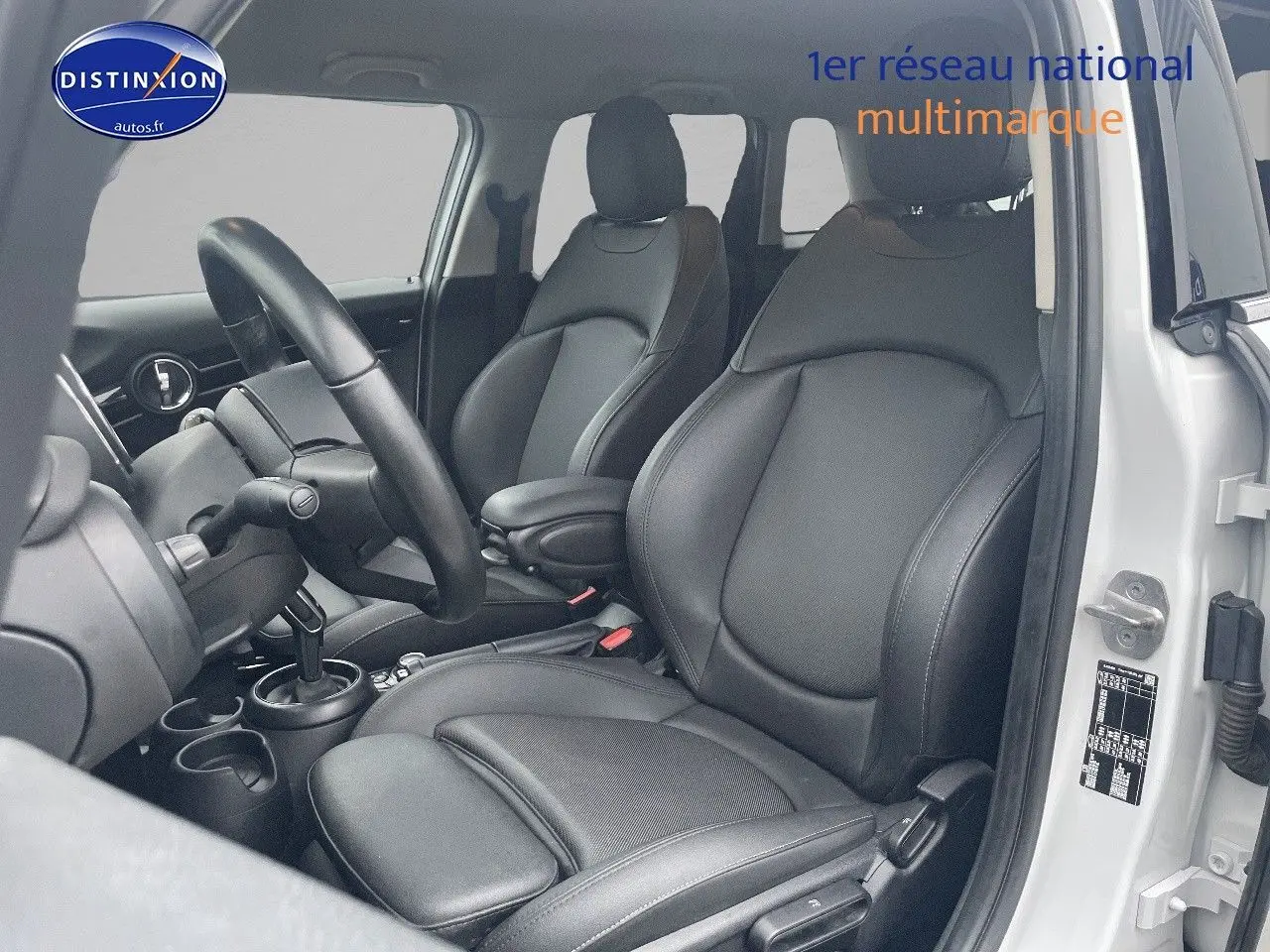 Intérieur de la MINI 1.5 136CH blanc nacré, vue côté conducteur montrant sièges en cuir noir et volant.