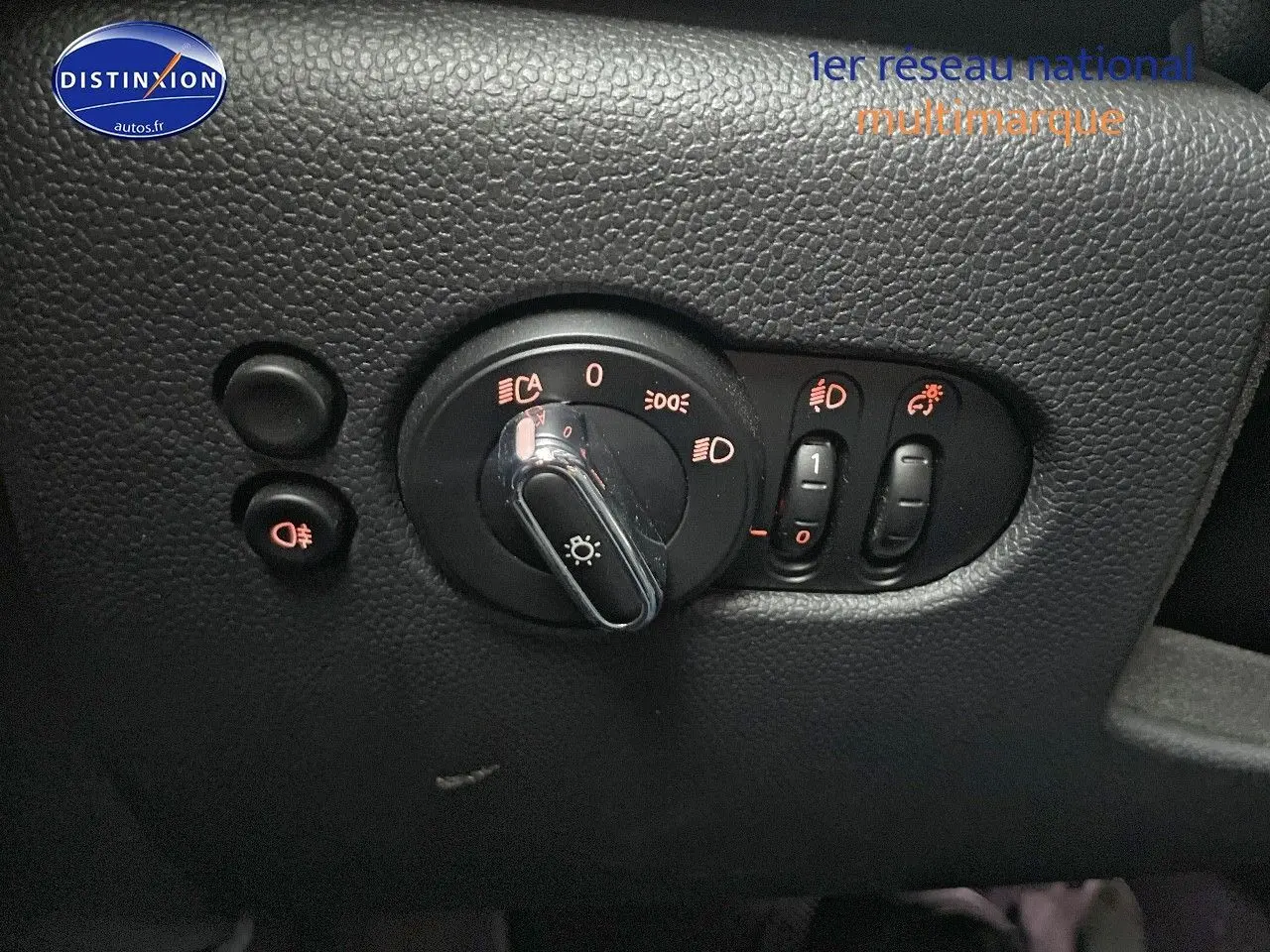 Gros plan sur les commandes d'éclairage intérieures d'une MINI blanche nacrée 2023, avec boutons rétroéclairés rouges.