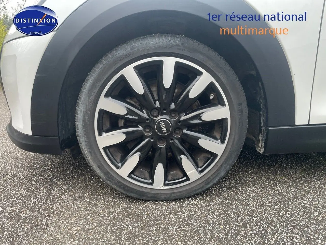 Gros plan sur la roue avant droite d'une MINI blanche nacrée avec jante noire et argentée au design distinctif.