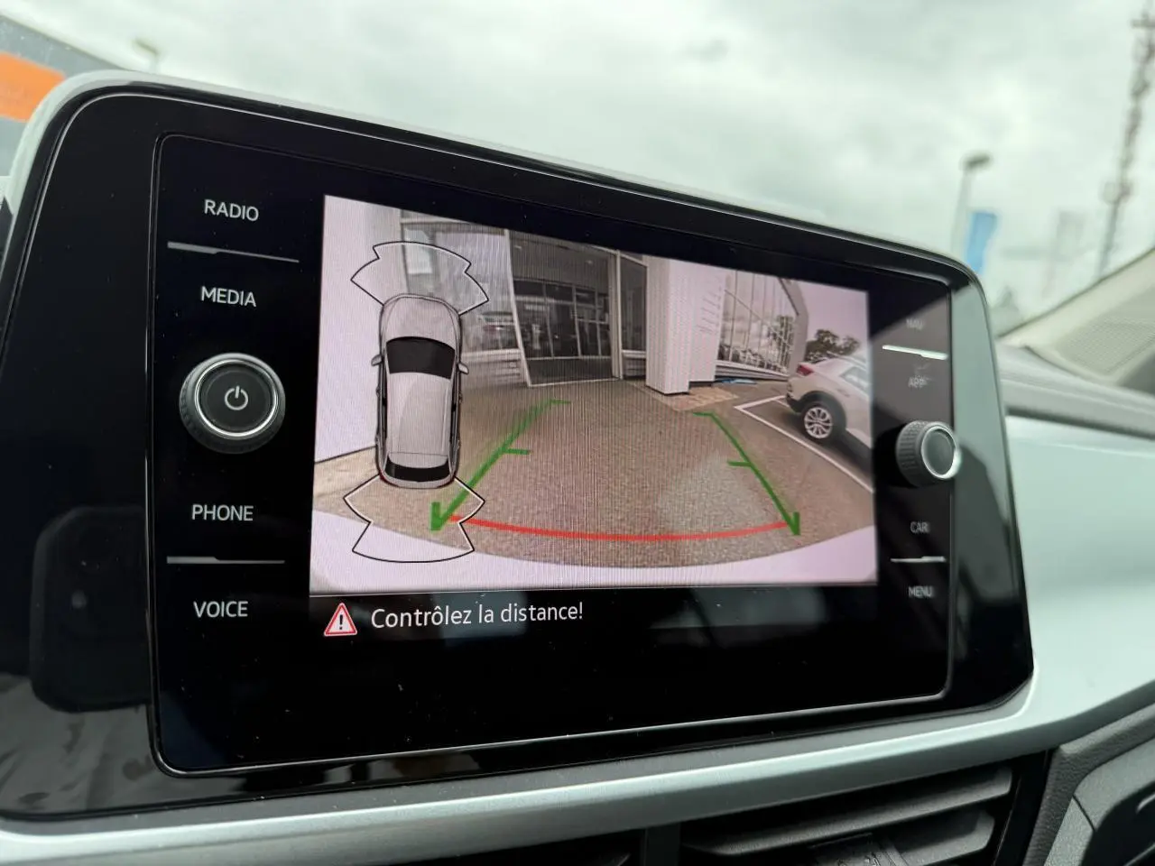 Écran de caméra de recul du Volkswagen T-Roc blanc pur montrant l’arrière et les lignes de guidage vertes et rouges.