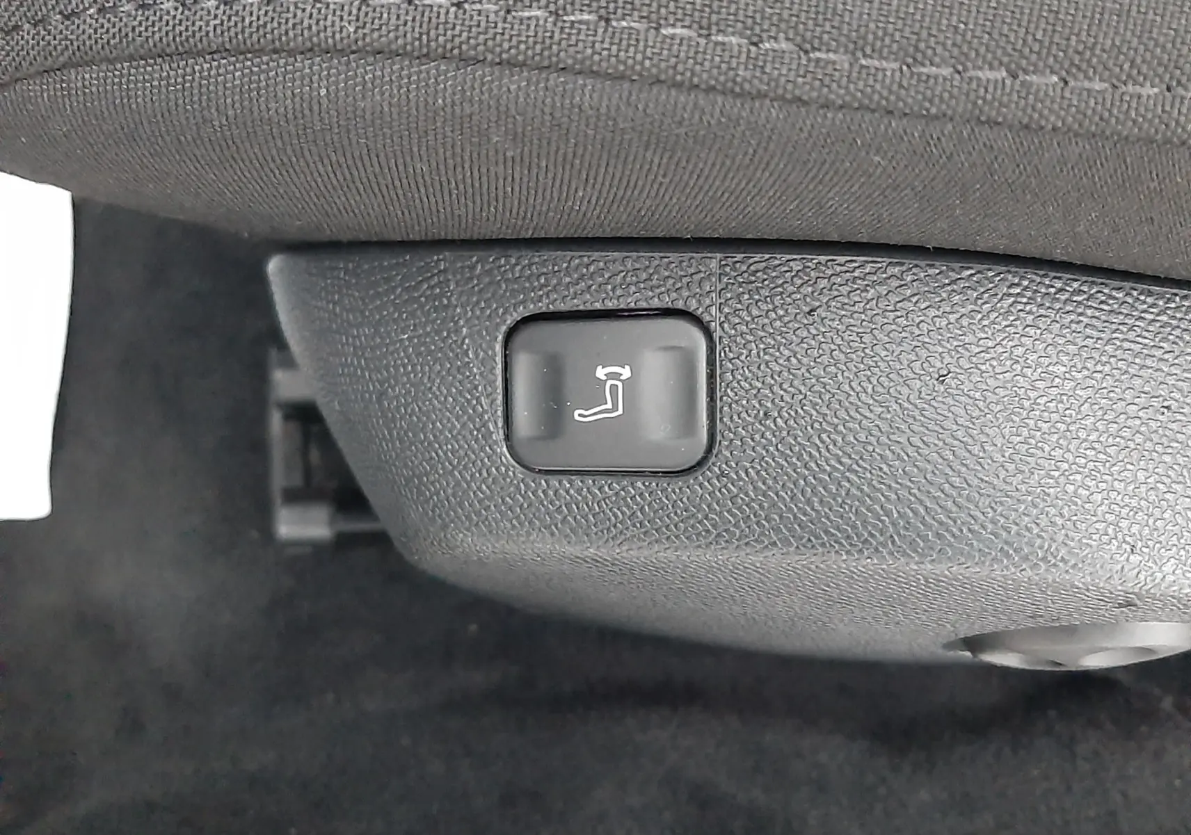 Bouton de réglage électrique de l'inclinaison du siège avant dans une Peugeot 508 blanche, version 1.5 BlueHDi 130 Active.