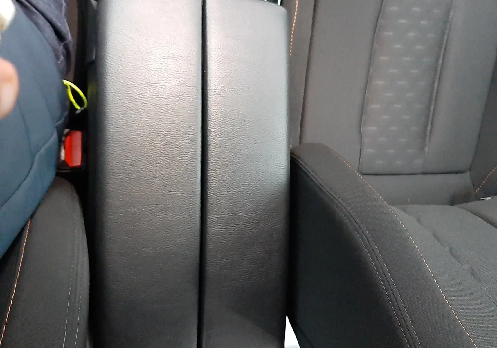 Vue rapprochée de l'accoudoir central noir entre les sièges avant gris foncé du Peugeot 508 blanc de 2018.