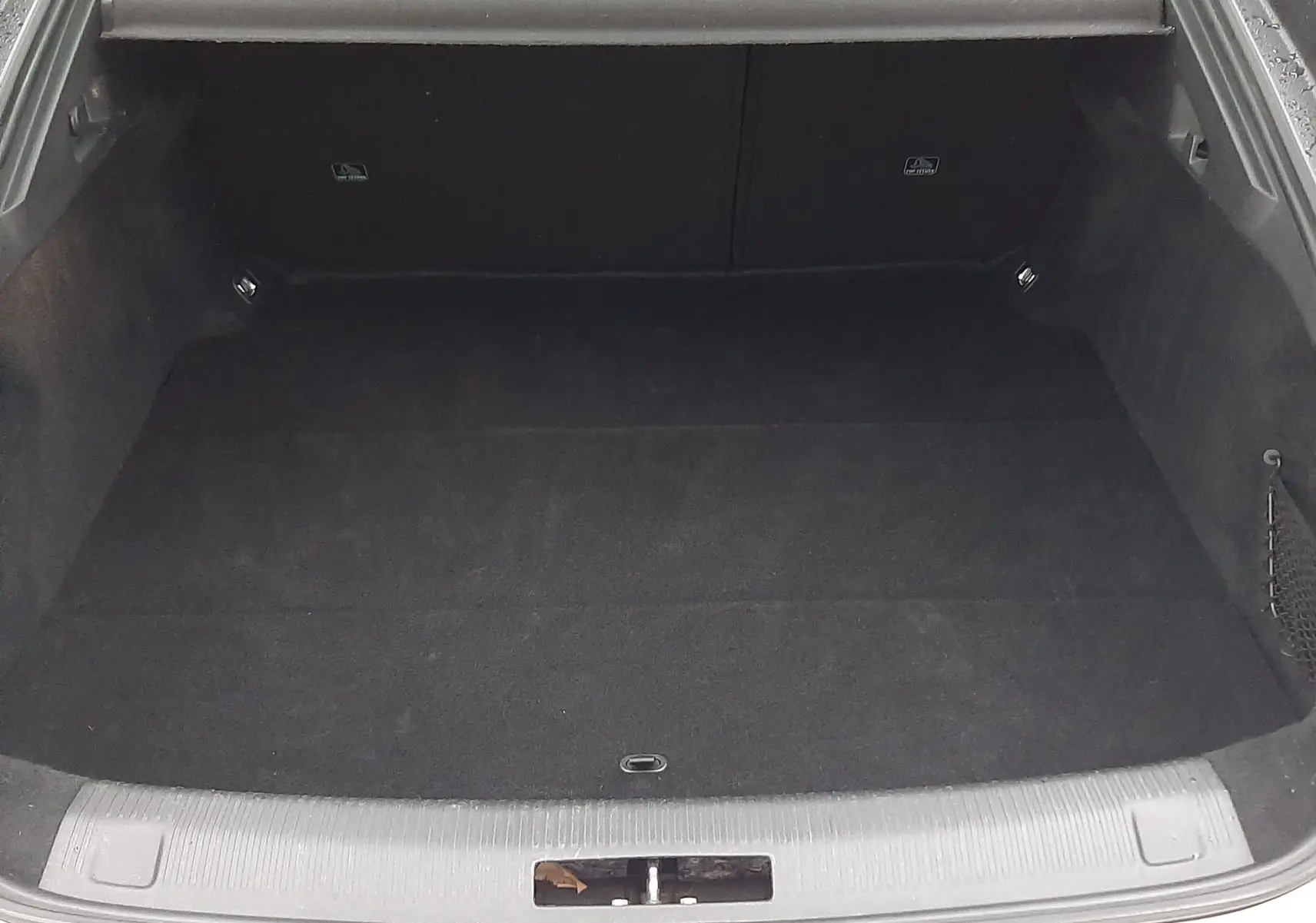 Coffre ouvert vu de l'arrière d'une Peugeot 508 blanche, espace de chargement vide avec cache-bagages noir.