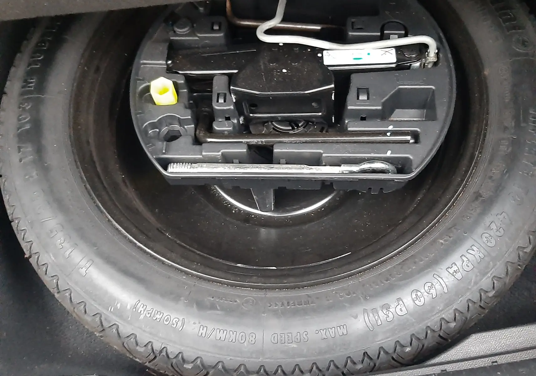 Gros plan sur la roue de secours et le kit d'outils dans le coffre d'une Peugeot 508 blanche 1.5 BlueHDi 130 de 2018.