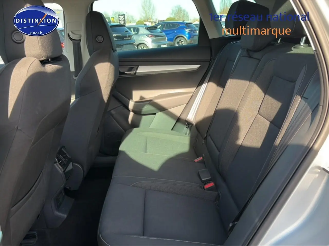 Vue intérieure côté droit des sièges arrière noirs du Skoda Karoq gris 2025 avec accoudoir central et ceintures visibles.