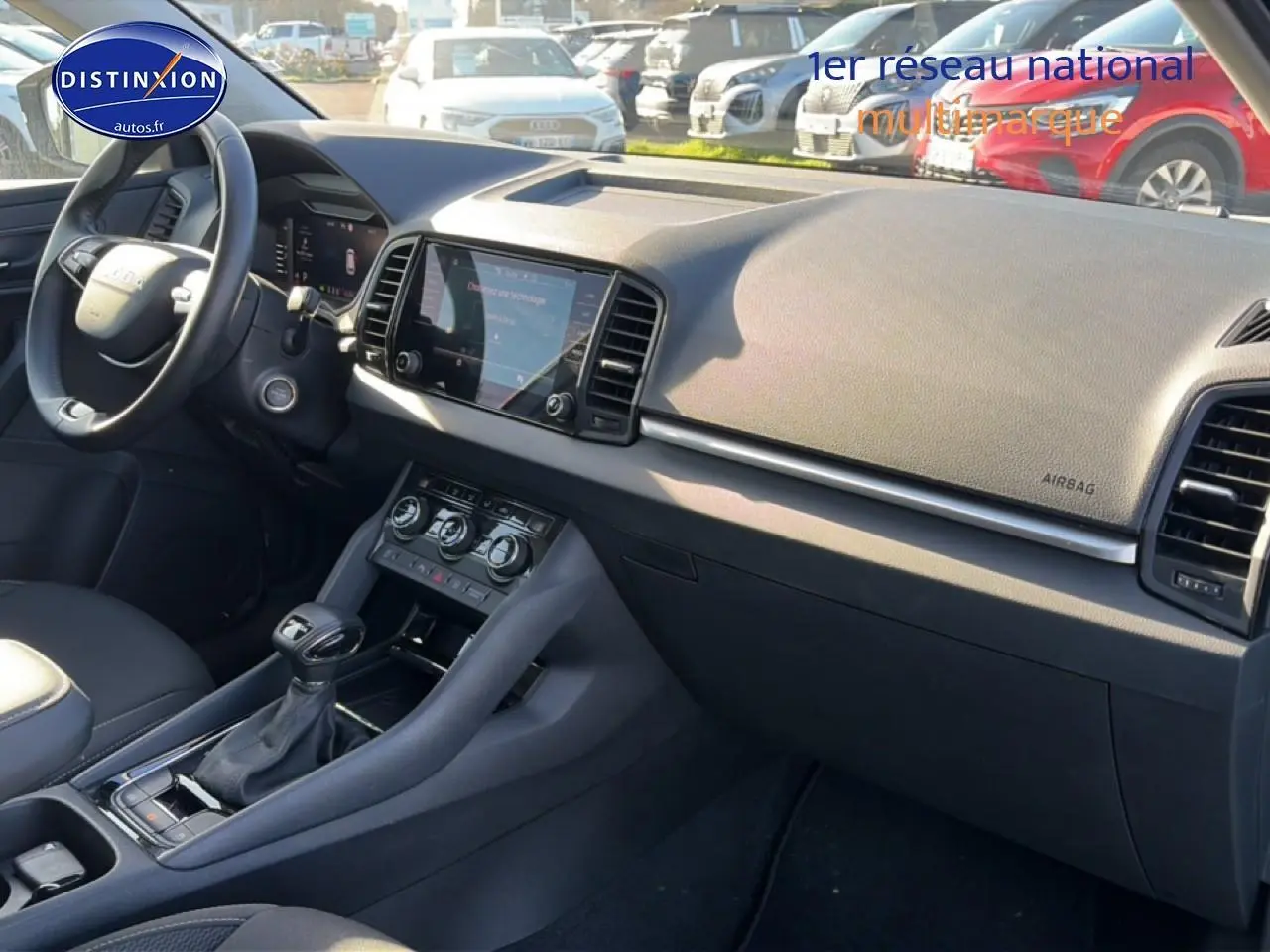 Vue intérieure côté passager du tableau de bord et console centrale du Skoda Karoq gris 2025 avec écran tactile et volant multifonction.