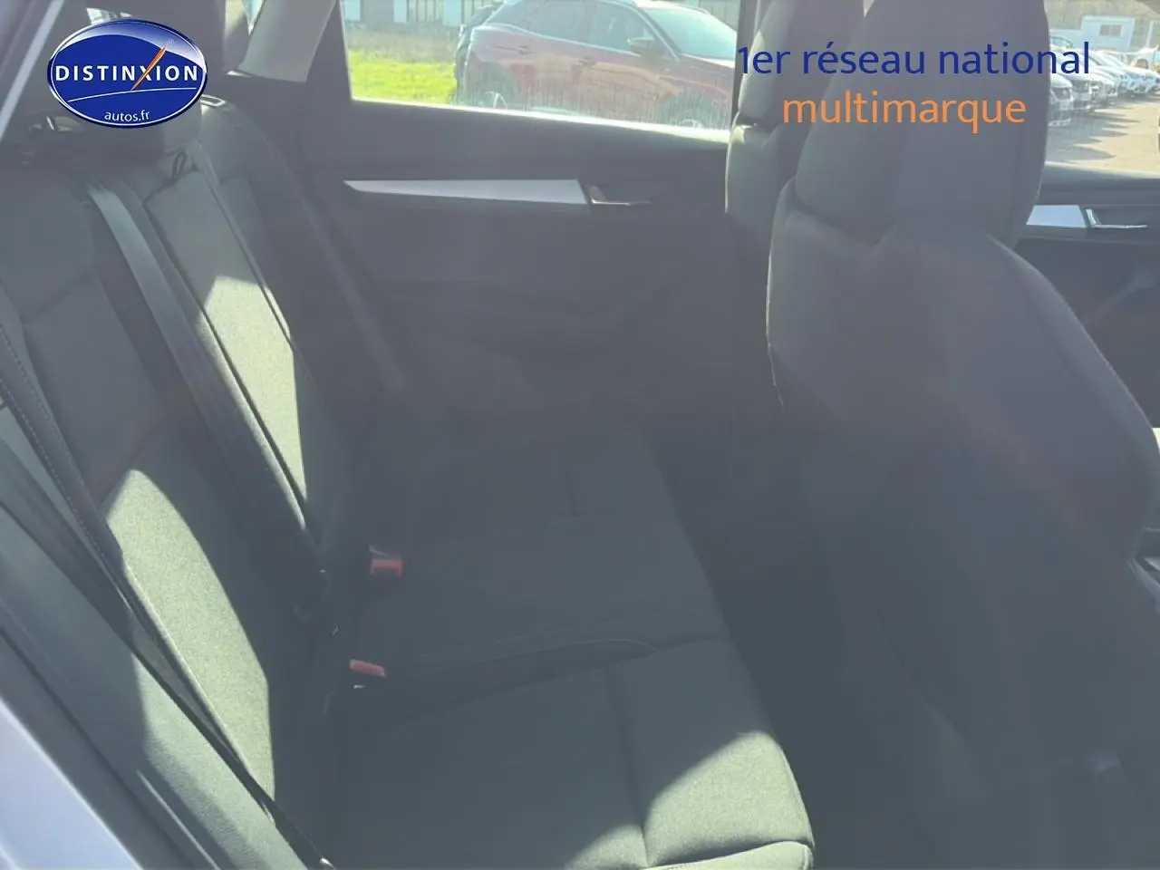 Vue intérieure côté arrière gauche du Skoda Karoq gris, montrant la banquette arrière et les sièges avant.