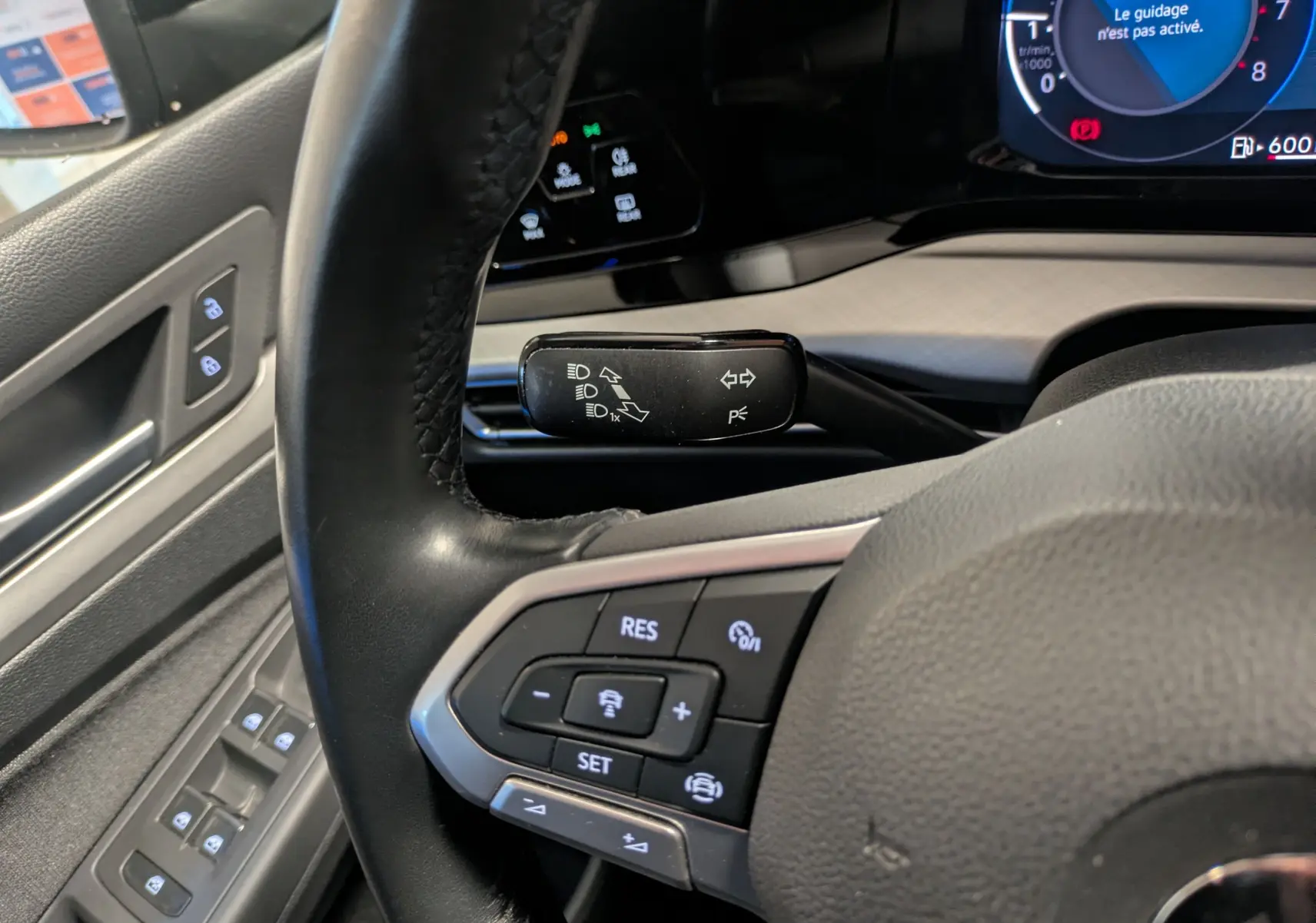 Vue rapprochée du volant côté gauche d’une Volkswagen Golf 1.5 eTSI noire 2024, avec commandes au volant et levier de clignotant.