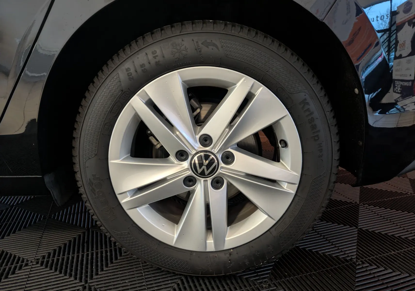 Gros plan sur la roue avant gauche d’une Volkswagen Golf 1.5 eTSI Style noire de 2024 avec jante alliage argentée.