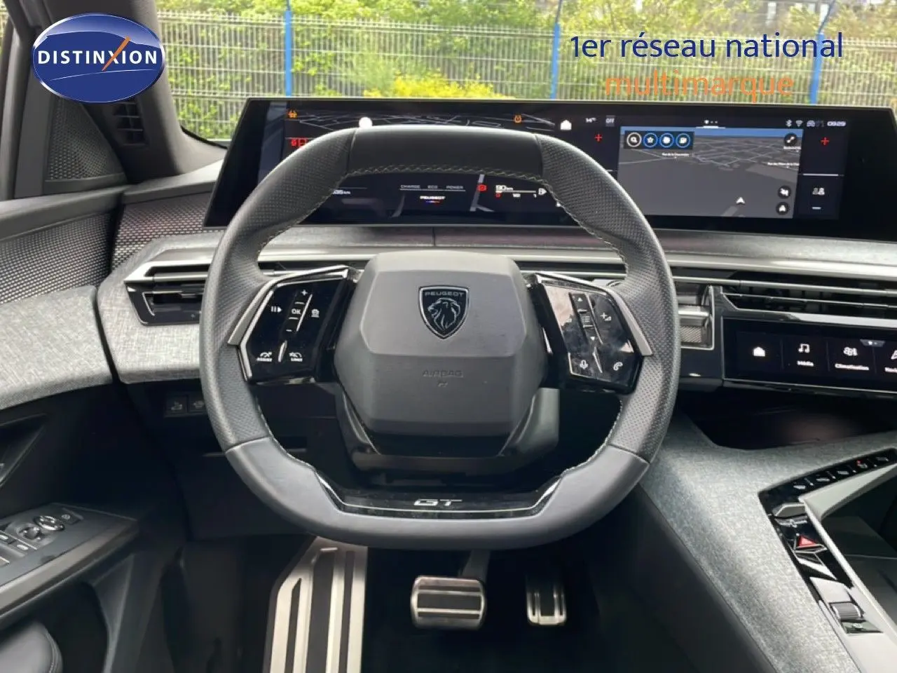 Vue intérieure frontale du volant GT en cuir perforé et des écrans numériques larges du Peugeot 3008 gris Artense 2025.