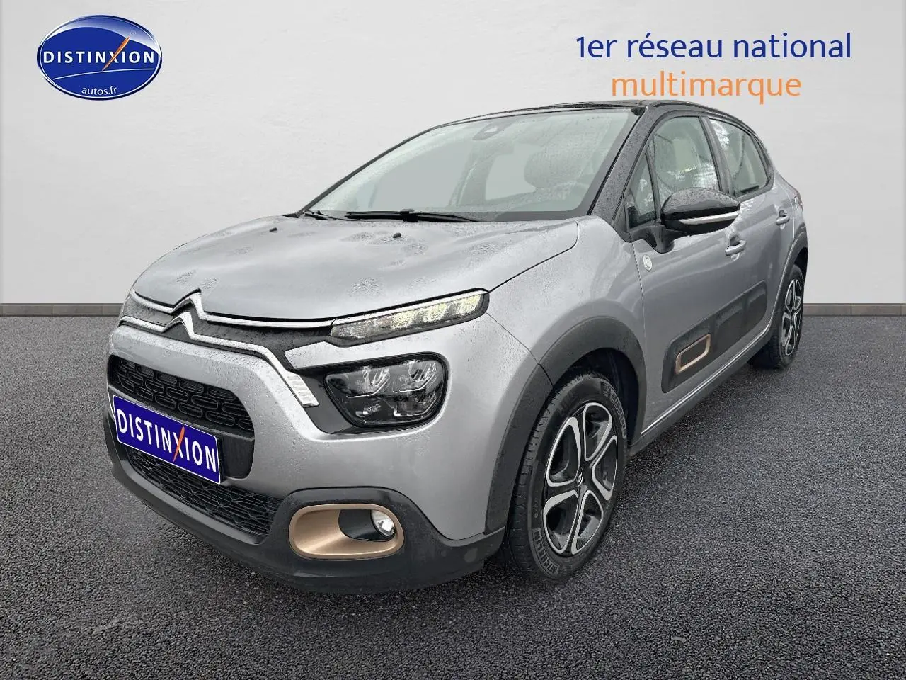 Citroën C3 gris acier vue 3/4 avant droit avec enjoliveurs noirs et détails couleur bronze sur pare-chocs et portières.