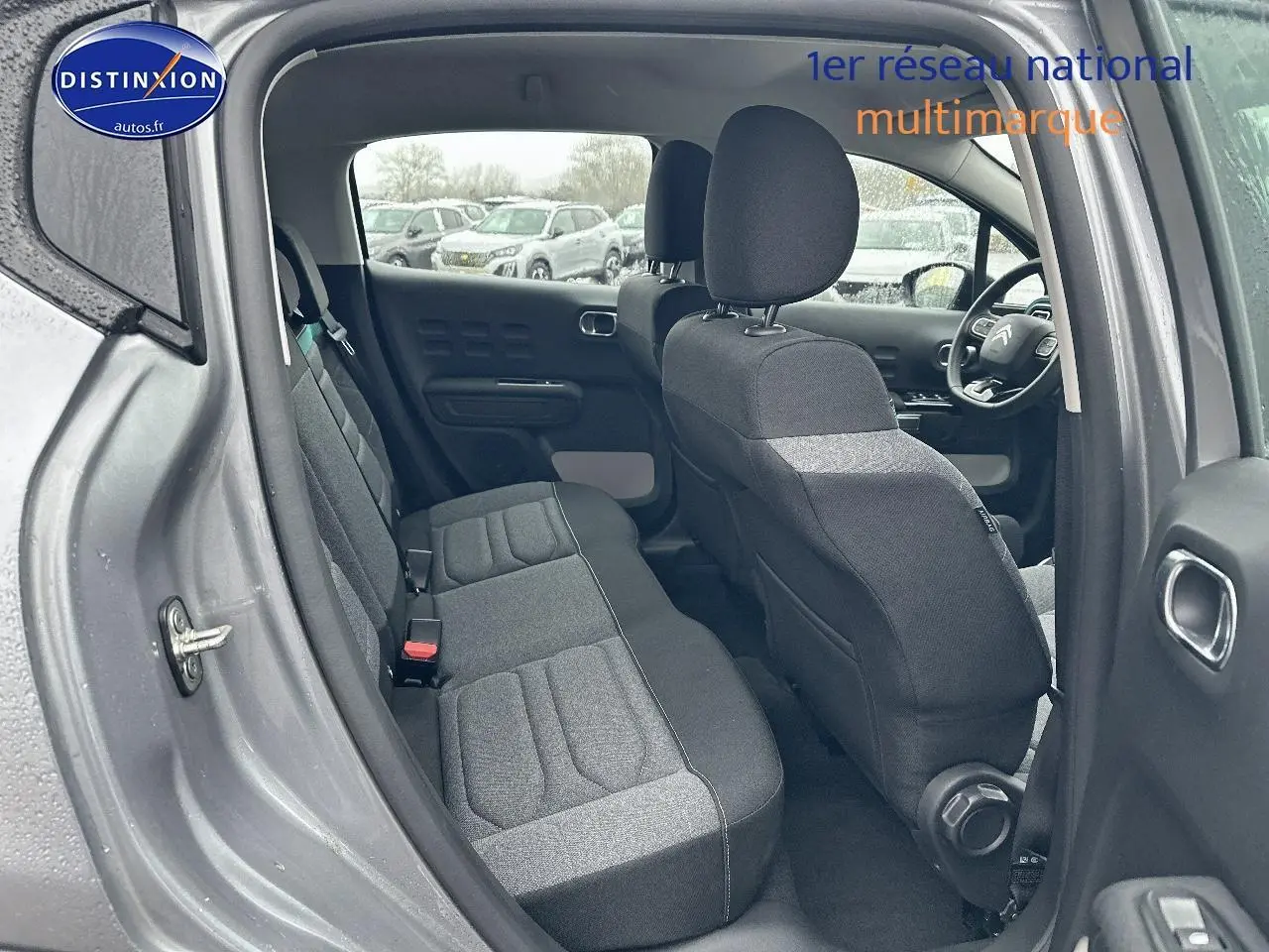 Vue intérieure côté gauche montrant les sièges arrière et avant en tissu gris d'une Citroën C3 gris acier 2023.