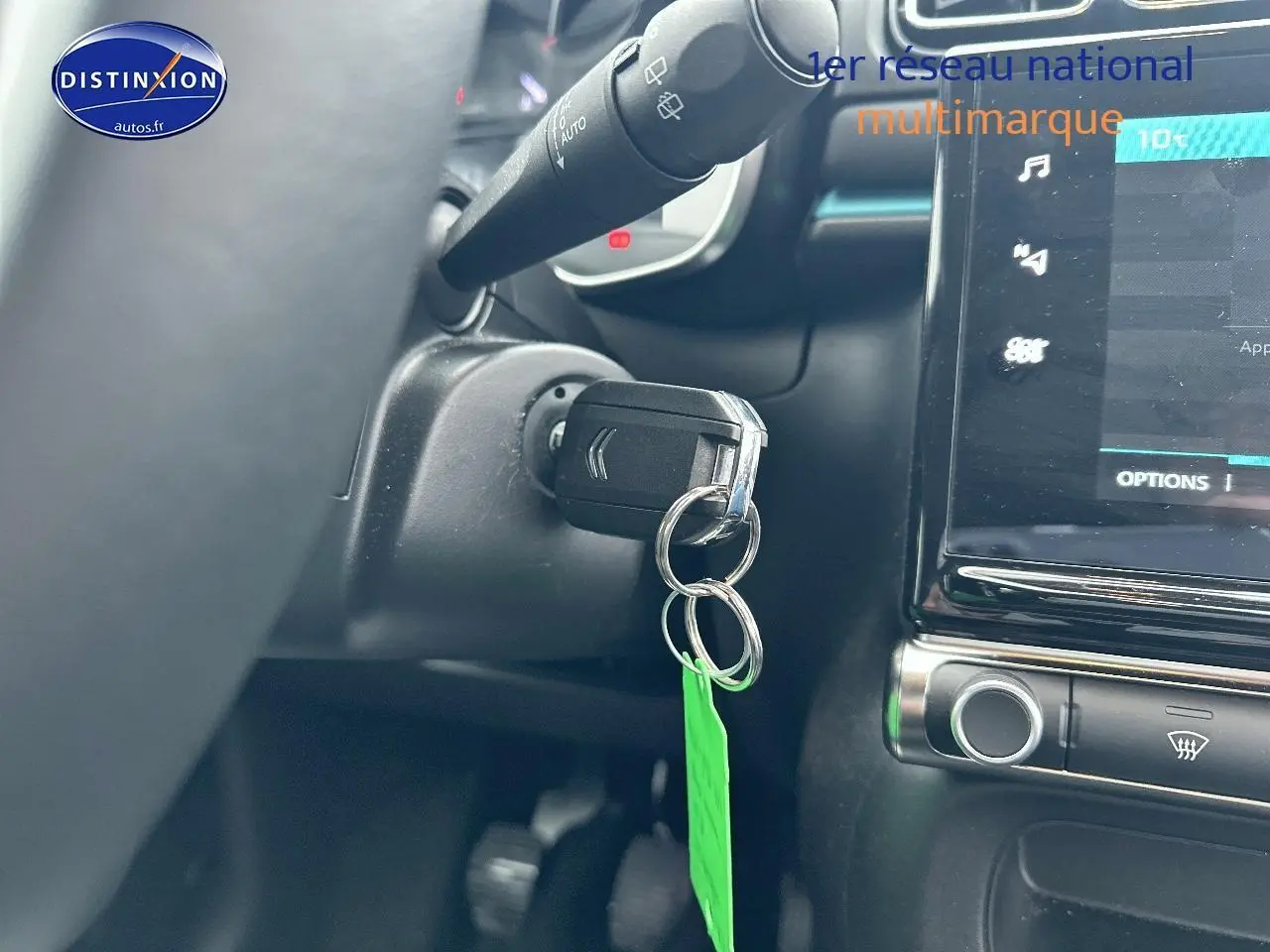 Gros plan intérieur sur le contacteur de clé et l’écran tactile d’une Citroën C3 gris acier, version 2023.