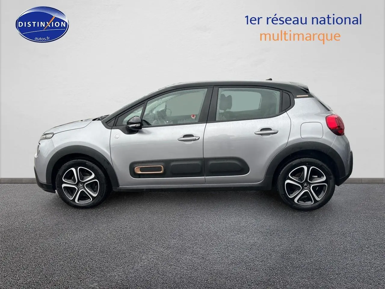Profil droit d'une Citroën C3 gris acier 2023 avec protections latérales noires et jantes alliage bicolores.