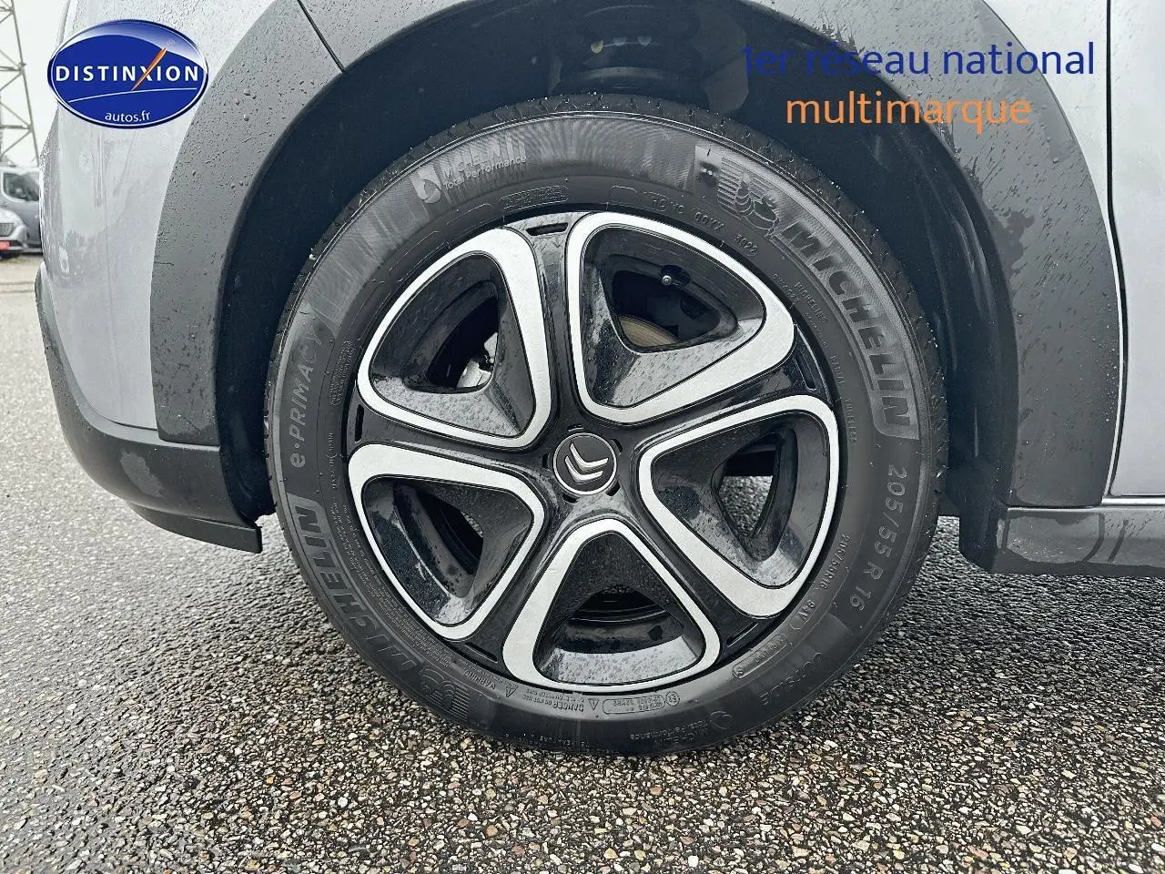 Gros plan sur la roue avant gauche avec jante alliage noire et argentée d'une Citroën C3 gris acier.