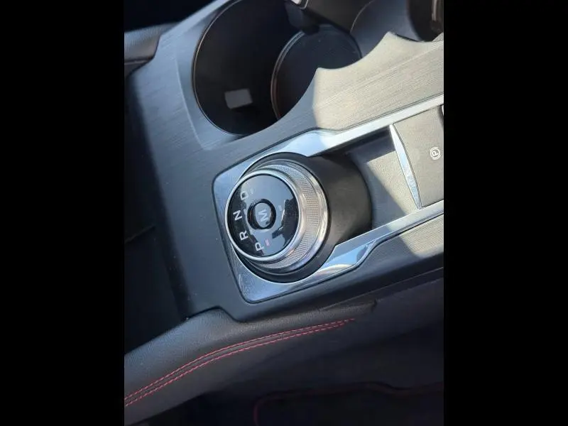 Gros plan sur la molette de sélection de la boîte automatique dans l’habitacle noir du Ford Kuga gris Solar Métallisée.