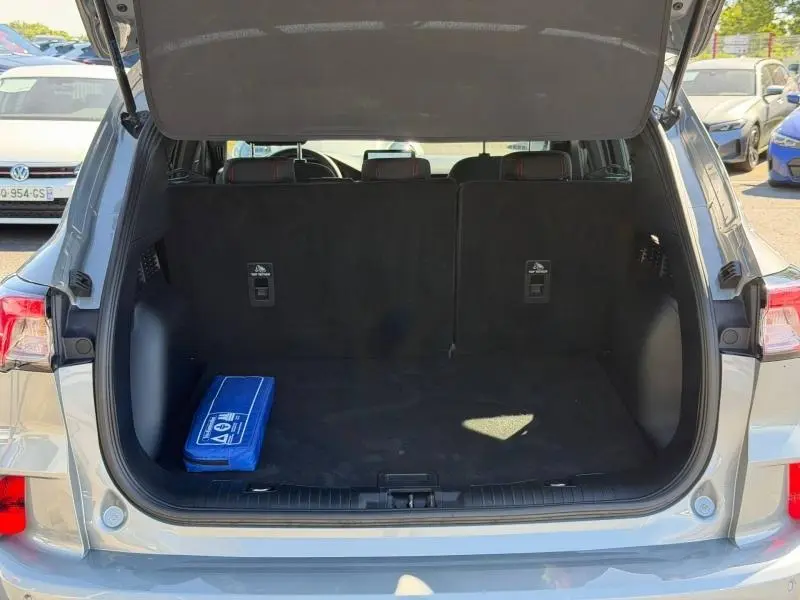 Coffre ouvert vu de l'arrière d'un Ford Kuga gris Solar Métallisé, avec un kit de secours bleu à gauche.