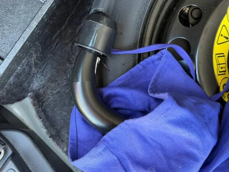 Détail du crochet d'attelage noir partiellement recouvert d'un tissu bleu dans le coffre du Ford Kuga gris Solar Métallisée.