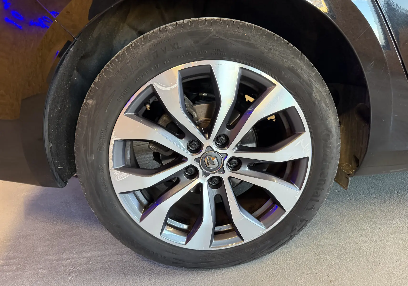 Gros plan sur la roue avant droite d’une Renault Mégane Estate noire, avec jante alliage à design moderne et logo central Renault.