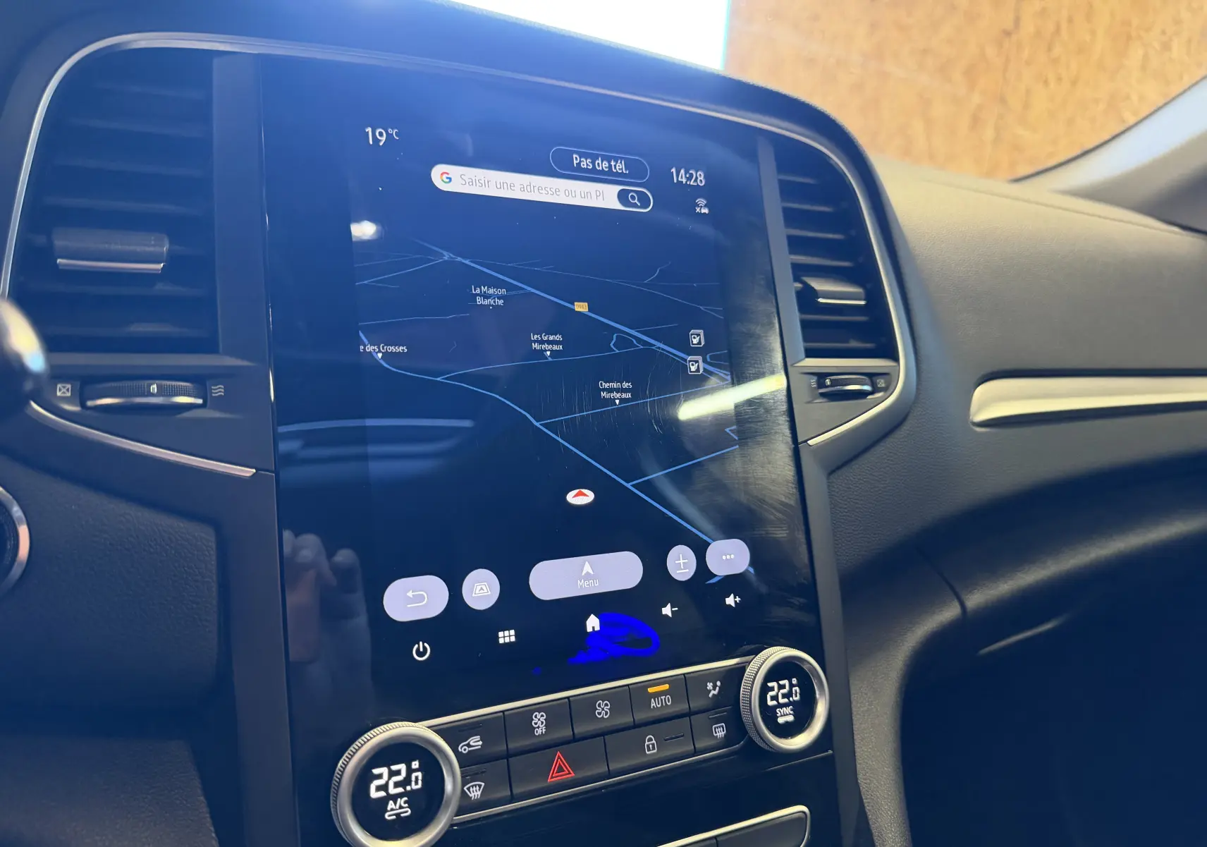 Vue rapprochée de l’écran tactile central et de la console de la Renault Mégane Estate 2024, affichant la navigation et la climatisation.