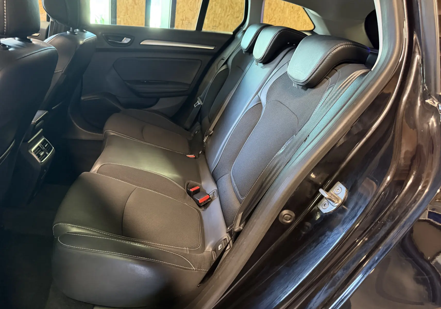Vue côté droit des sièges arrière noirs en tissu et cuir de la Renault Mégane Estate 2024, porte ouverte.