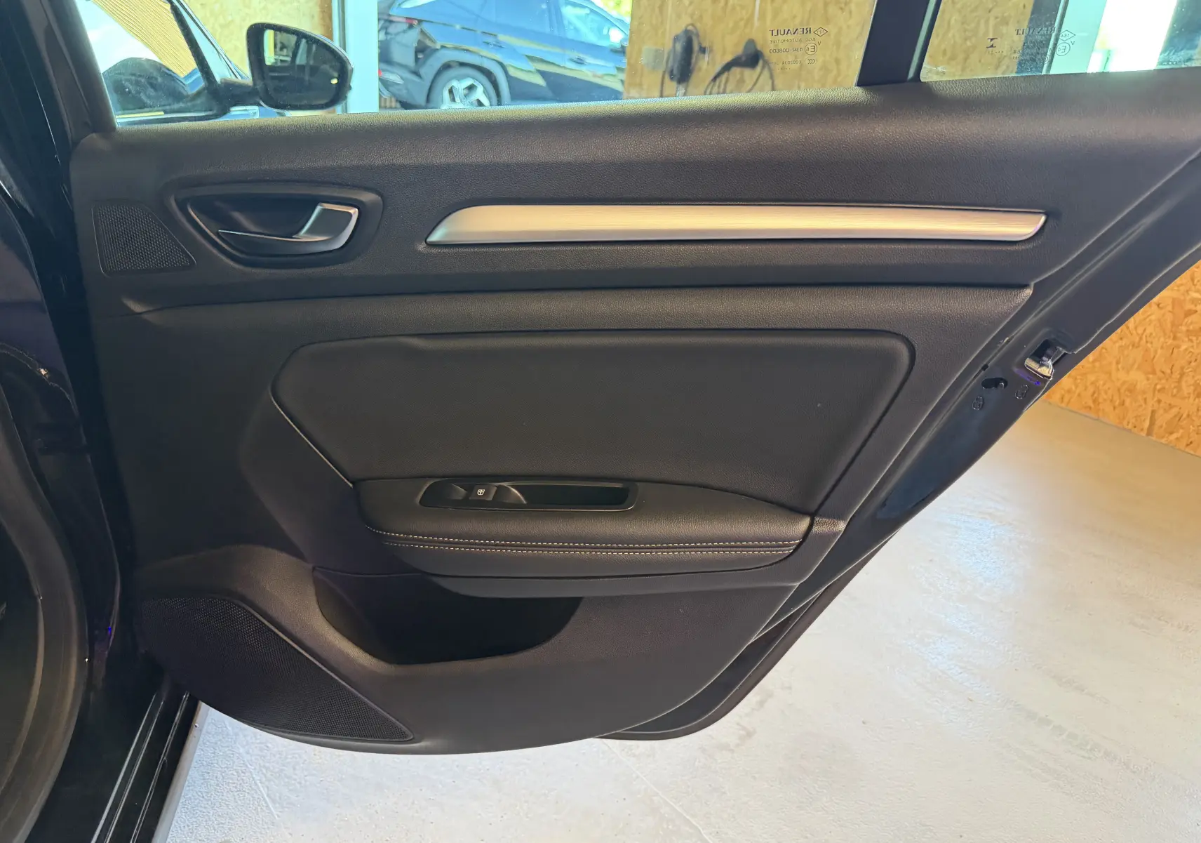 Vue intérieure de la porte arrière gauche noire de la Renault Mégane Estate 2024 avec garniture en cuir et insert métallique.