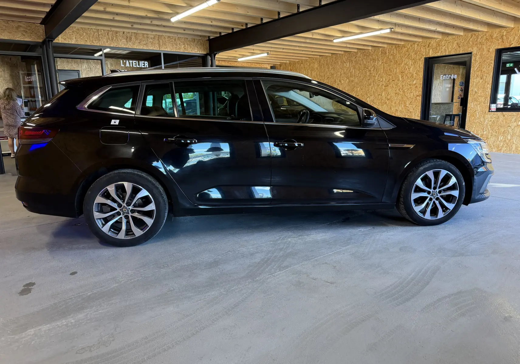 Profil côté gauche d'une Renault Mégane Estate noire étoilée 2024, avec jantes alliage et toit ouvrant panoramique visible.