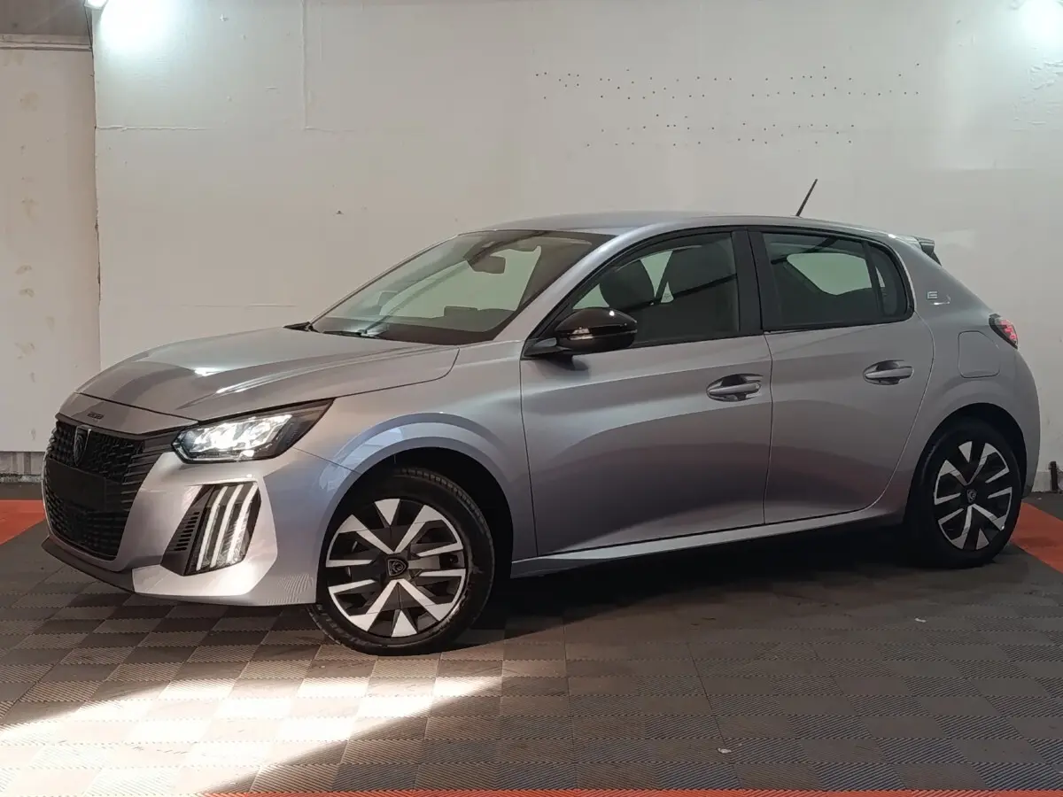 Peugeot 208 électrique gris clair vue de profil droit, avec phares LED et jantes stylisées noires et argent.